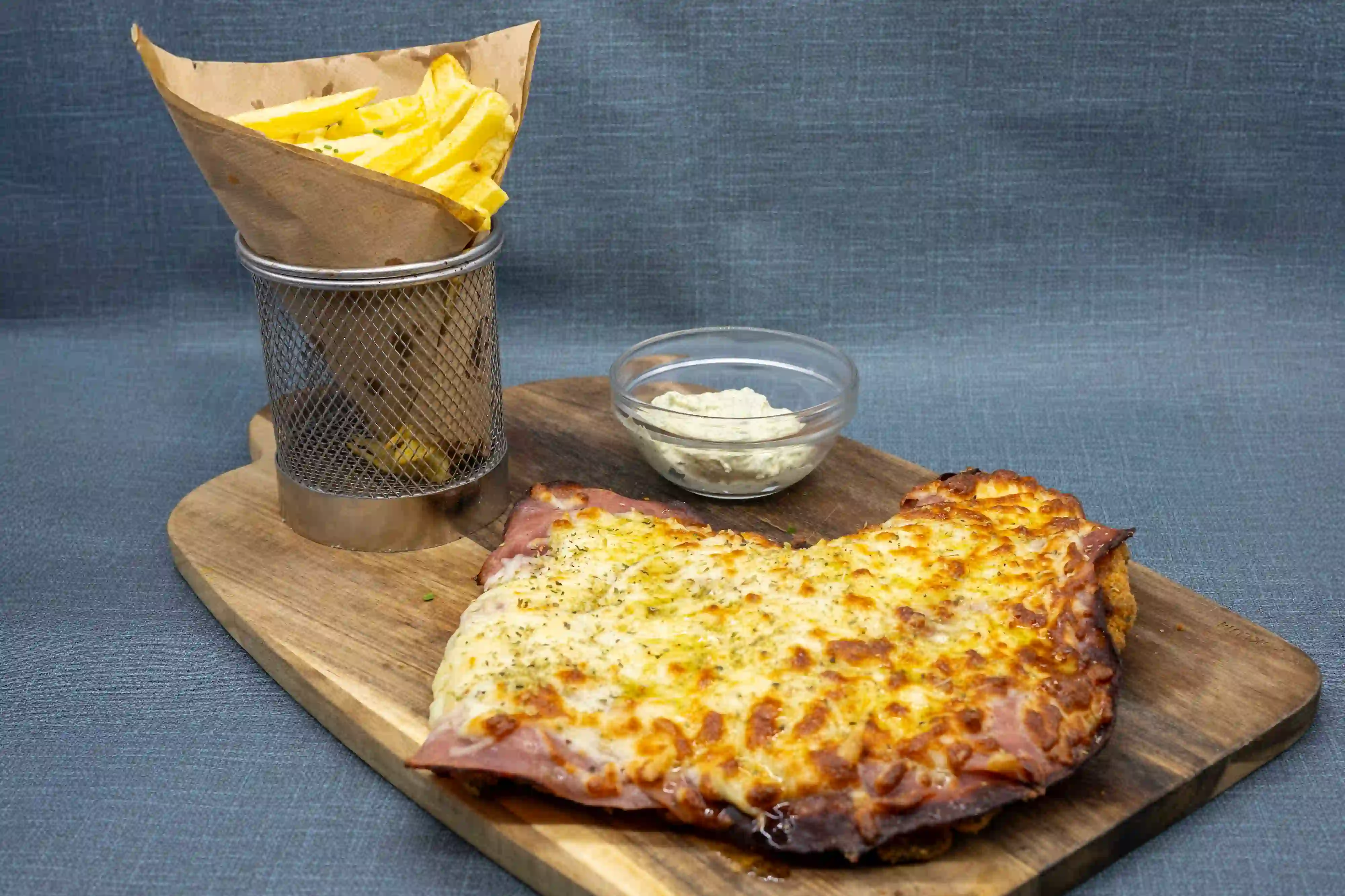 Milanesa gratinada con jamón y queso fundido, salsa de tomate y patatas fritas